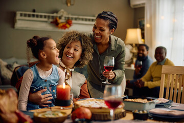 Happy black girl has fun with her grandmother and mother on Thanksgiving.