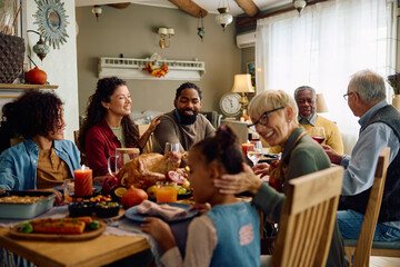 Happy multiracial extended family celebrates Thanksgiving at dining table. - obrazy, fototapety, plakaty