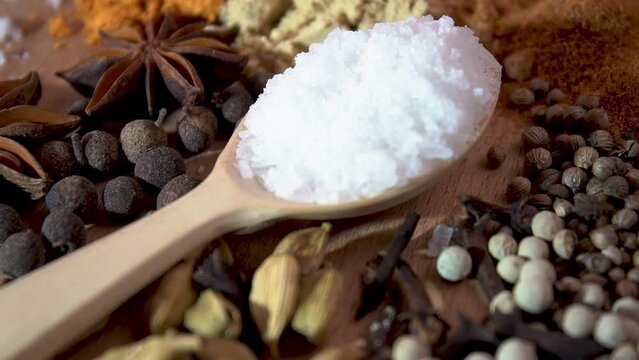 Natural spices and salt. Large salt crystals in a wooden spoon near the spices. Close-up. Black pepper, cumin, coriander, turmeric, salt. Coarse salt for marinating.