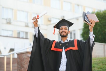 Handsome indian graduate in graduation glow with diploma.