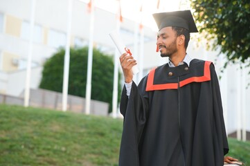 portrait of successful indian student in graduation gown.