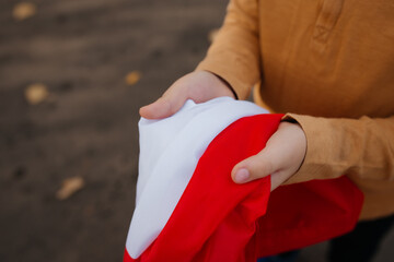 A little boy stands on the road and holds the flag of Poland in his hands. Close-up of child's...
