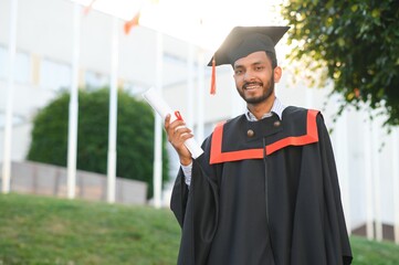 Portrait of indian handsome male graduate in graduation robe.