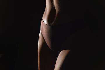 Cropped image of female body, muscular belly, leg. Model standing in underwear. Studio background....