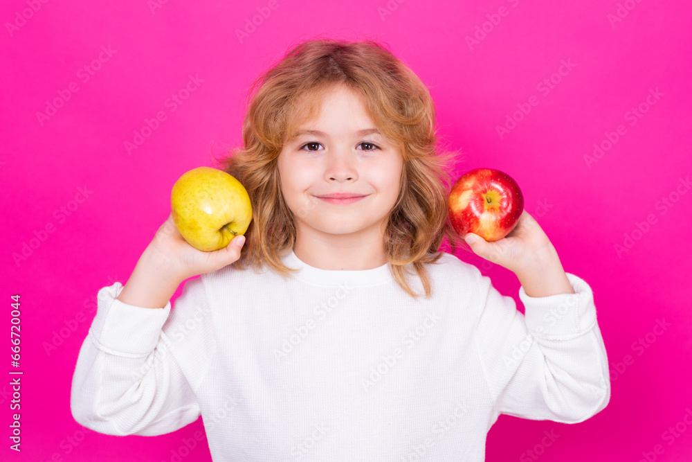 Wall mural Kid with apple in studio. Studio portrait of cute child hold apple isolated on pink background.