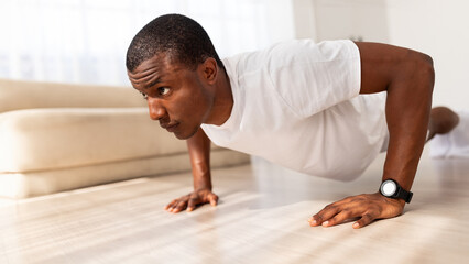 Fototapeta na wymiar Black man exercising in his house gym, doing push ups