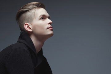 Male beauty concept. Fashionable young man with stylish haircut wearing trendy black sweater,...