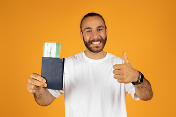 Satisfied millennial european man in white t-shirt shows passport and tickets, enjoy lifestyle