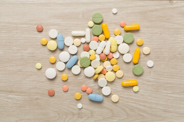 Different medical pills and capsules on wooden background, top view