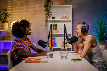 Two content creators are sitting in a home recording studio and making a podcast