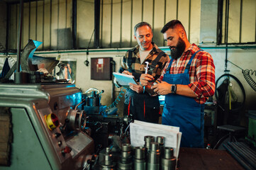 Two metal turners talking about a roll cut by a lathe machine.