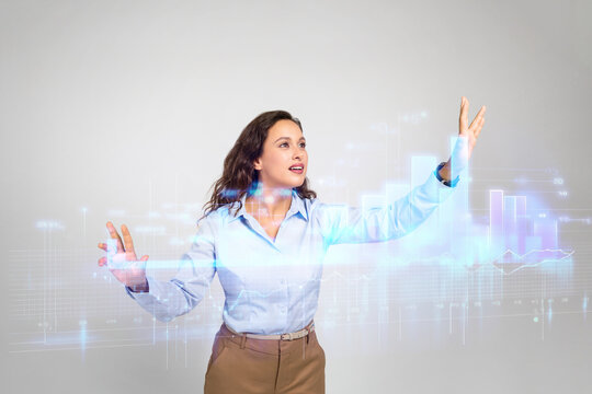 Focused millennial european business woman in formal wear controls abstract digital virtual screen with graphs