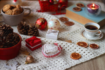 Obraz na płótnie Canvas Various colorful Christmas decorations, soft blanket, cup of tea, sweet snacks and lit candles on the table. Cozy Christmas atmosphere at home. Selective focus.