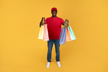 Happy millennial black guy courier hold many boxes with purchases