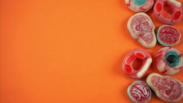Orange background on one side of which Halloween candies appear. Stop motion animation