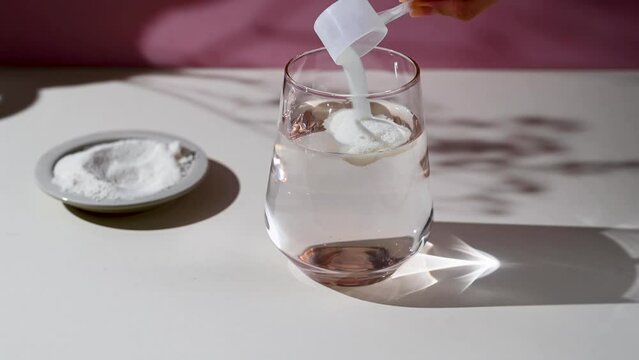 Collagen protein powder pouring in a glass with water. Food beauty and health supplement