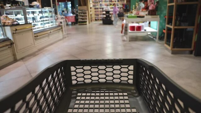 Close up cropped black empty trolley cart moving in contemporary supermaket store grocery shop ready for buying choosing products inside hypermarket. Purchasing food gastronomy goods shopping concept