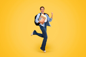 Fototapeta na wymiar Happy young european lady with backpack and books jump, freeze in air, enjoy student lifestyle, win