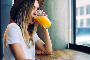 Young lady enjoying juice in front of window