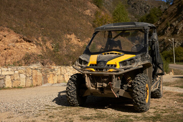 A cross-country vehicle (all-terrain vehicle) for off-road tourist trips on a road in the mountains. Close-up.