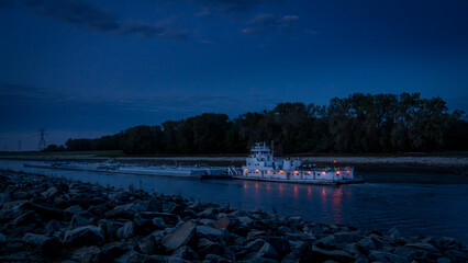 towboat with barges on Chain of Rock Bypass Canal of Mississippi River above St Louis, night scenery at dawn