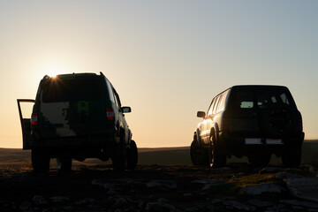 Two passenger cars on top of a mountain at dawn in the first rays of the rising sun. © ROMAN DZIUBALO