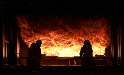 Two Firefighters practice to close the frame of fire and smoke from inside of the closed room