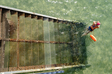 une nageuse quitte un vieil escalier rouillé qui rentre dans l'eau - 666754020