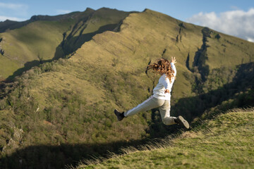 une jeune enfant saute en l'air dans le vide devant des montagnes