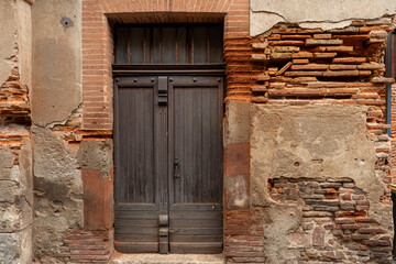une vieille porte en bois au milieu d'un mur en ruine avec des briques rouges  - 666755207