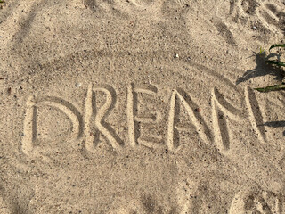 the word dream is written on the yellow river sand on the beach