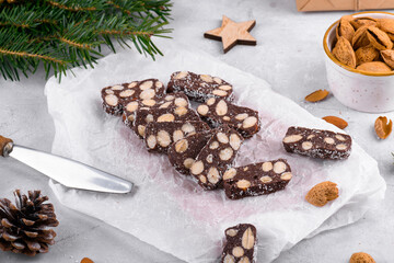 Sliced chocolate salami with almond on a baker paper, Christmas dessert sugar, gluten and lactose free. Homemade chocolate sausage, Dessert of Russian, Italian and Portuguese cuisines