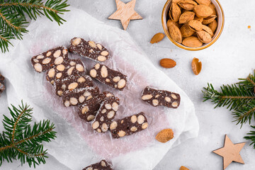 Sliced chocolate salami with almond on a baker paper, Christmas dessert sugar, gluten and lactose free. Homemade chocolate sausage, Christmas Culinary and Holiday Cuisine, top view, flat lay