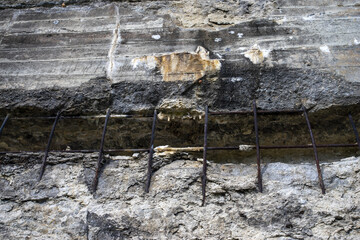 Żelbetonowa ściana z ubytkiem betonu odsłaniającym fragment stalowego zbrojenia © qrrr