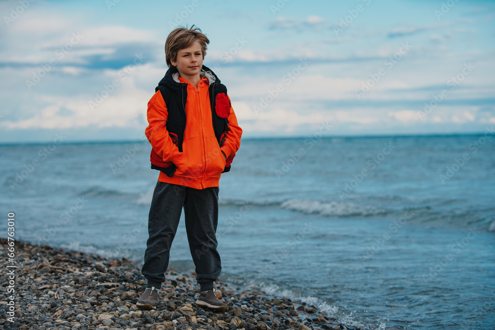 Sticker Boy tourist on the beach in cold weather