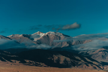 Picturesque landscape with mountain peaks in clouds at evening