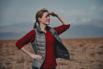 Young woman tourist in the mountains looking into the distance