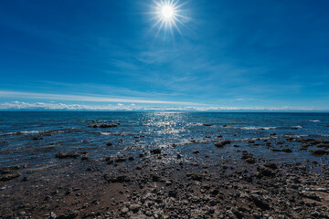 Rocky shore of lake in sunlight, wide angle view
