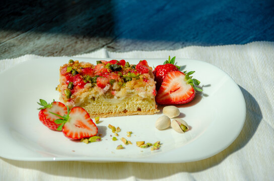 Rhabarberkuchen mit Erdbeeren und Pistazienauf eine weissen Teller