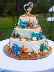 Tiered wedding cake with beach theme, adorned with starfish, seashells and coral