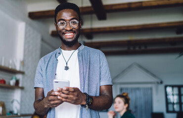 Content smiled African American man using smartphone at home