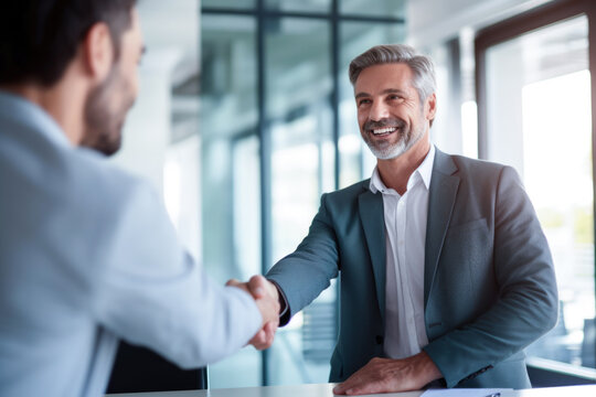 Smiling middle aged businessman handshaking partner making partnership collaboration agreement at office meeting.