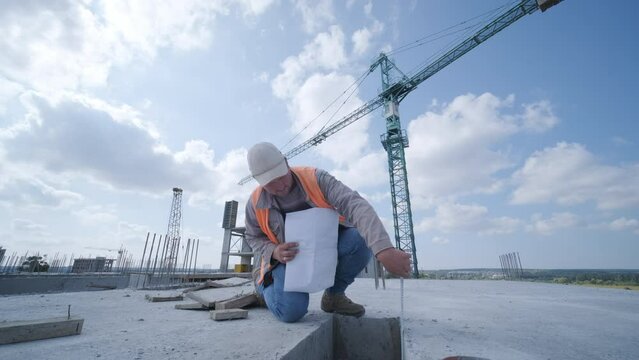 Inspector or engineer is inspecting construction and quality assurance check dimension of house by using a tape measurement. Engineers or architects or contactor work to build the house before sell.