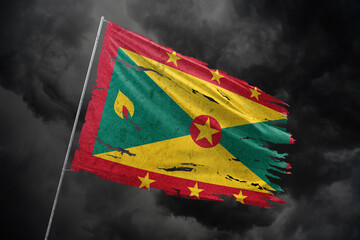 Grenada torn flag on dark sky background.