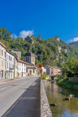 Fototapeta na wymiar Saint-Rambert-en-Bugey, France - 08 31 2021: Grand Colombier Pass. View of the Albarine river, the road, the church, the castle ruins and the mountain ridge .
