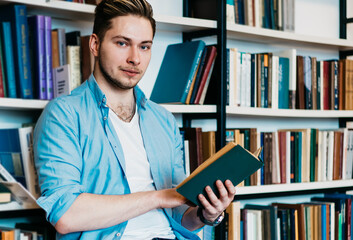 Serious guy reading book in library