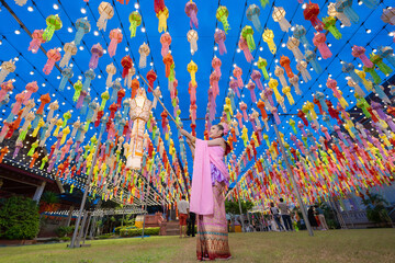 Lantern Festival or Yi Peng Festival in Hundred Thousand Lantern with the pretty Asian girl wearing beautiful Thai traditional dress Lanna style Phra That Hariphunchai temple Lamphun, Thailand. - obrazy, fototapety, plakaty