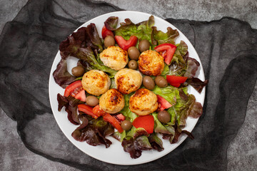 Chicken meatballs on lettuce with tomato and olives