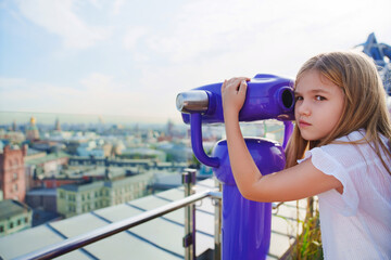 a teenage girl looks into the Binoscope from the observation deck at a height. 