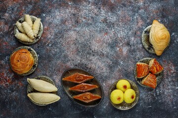 Traditional Azerbaijan holiday Novruz background with green semeni,traditional azerbaijan sweets,shekerbura,qogal,paxlava,mutaki and different nuts and sweets,top view,space for copy